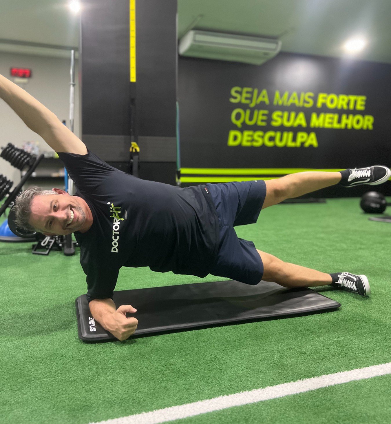 Personal trainer auxiliando aluno no estúdio DoctorFit