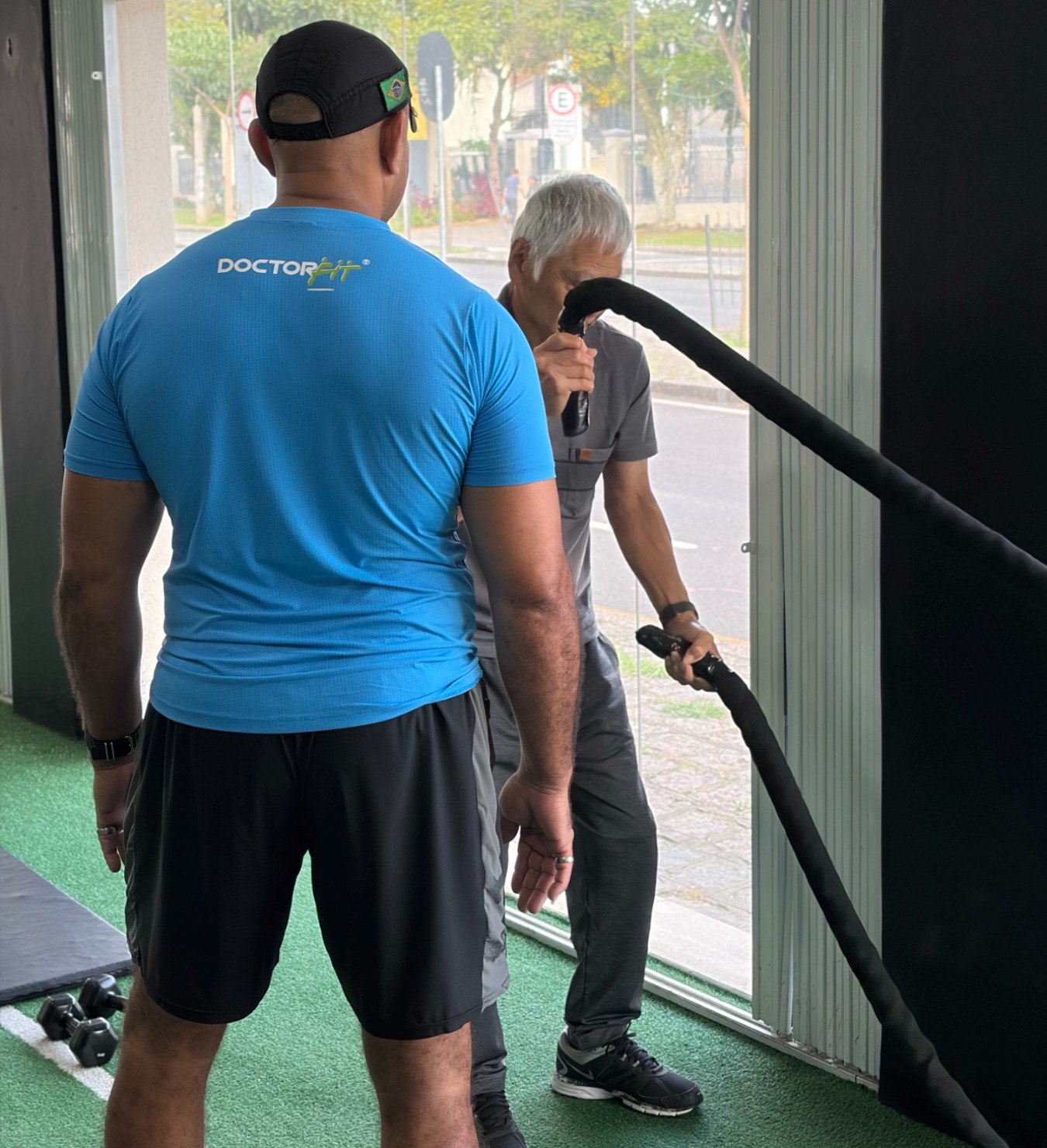 Personal trainer auxiliando aluno no estúdio DoctorFit