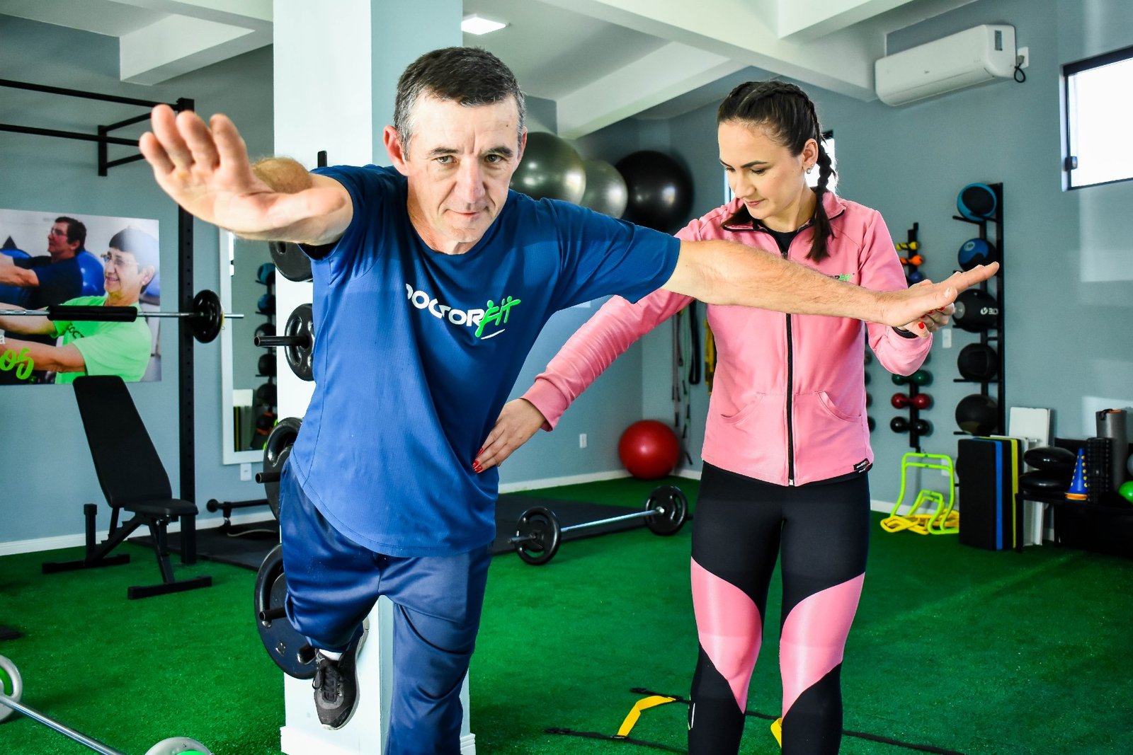 Personal trainer auxiliando aluno no estúdio DoctorFit